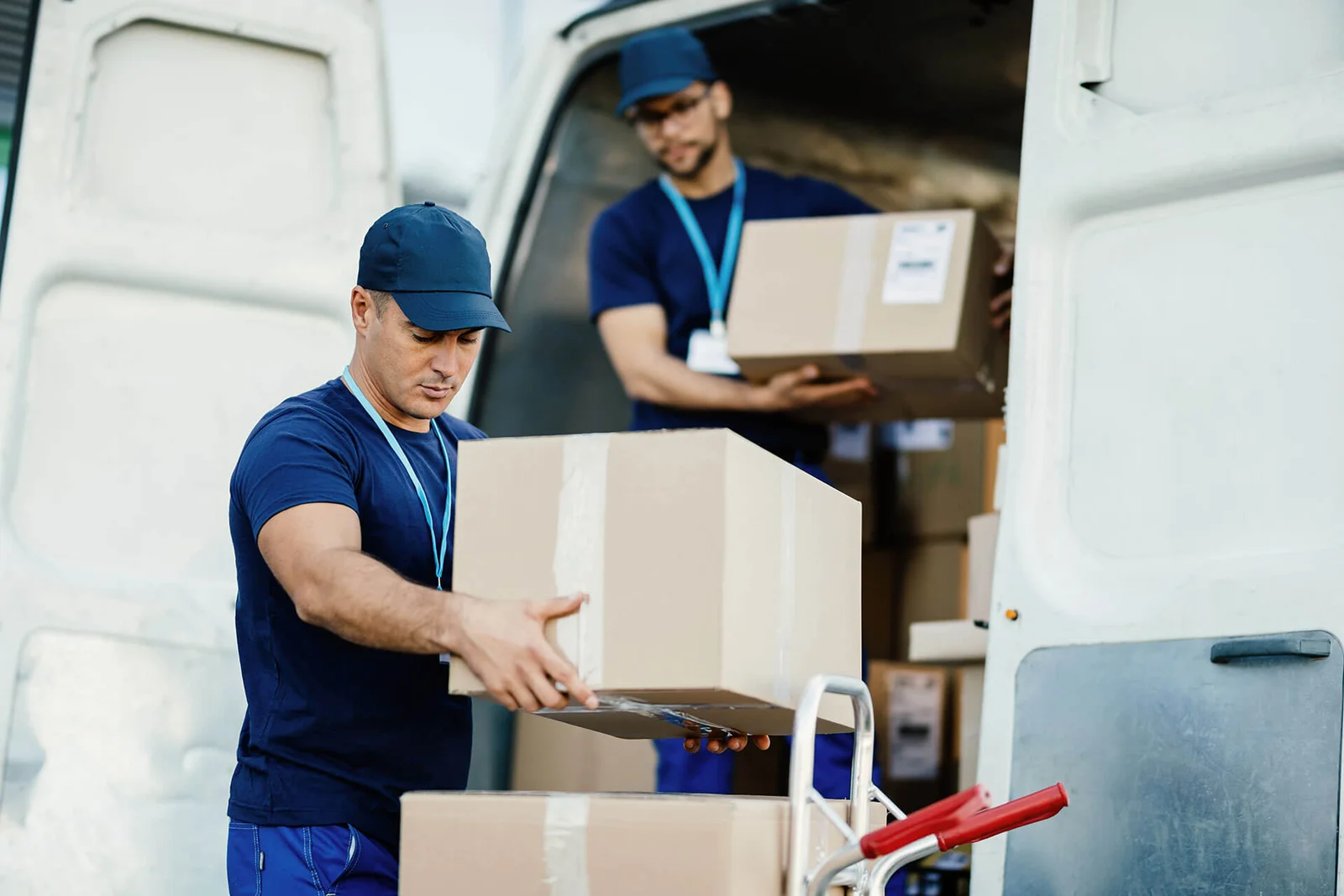 Two movers passing cartons into a van during a long-distance move